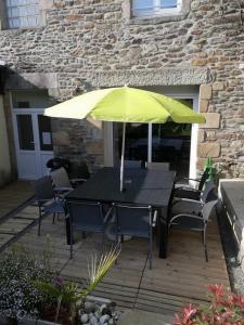 une table noire avec un parasol jaune sur une terrasse dans l'établissement LE COCON de MATIGNON Gîte 4 étoiles 5 kms mer, à Matignon