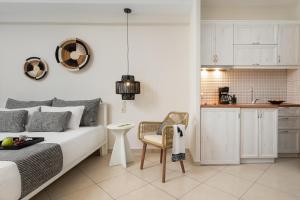 a bedroom with a bed and a chair and a kitchen at Ormos Holiday Studios in Naxos Chora