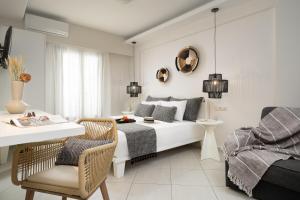 a white bedroom with a bed and a table and chairs at Ormos Holiday Studios in Naxos Chora