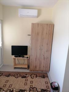 Zimmer mit einem TV und einem Holzschrank. in der Unterkunft Къща за гости Релиса in Razgrad