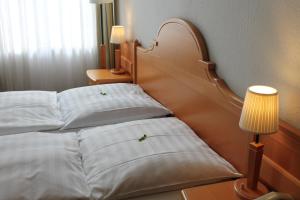 a bed with two green plants on the pillows at Hotel Weidenhof in Düsseldorf