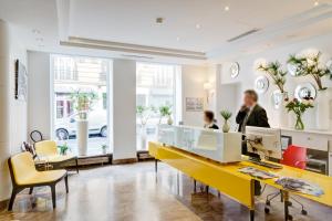 a lobby with a yellow counter and people in a room at Hotel Astoria - Astotel in Paris