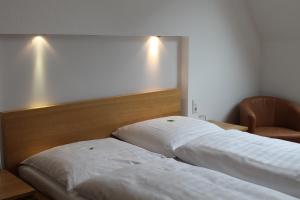 Hotel Weidenhof في دوسلدورف: سريرين بيض في غرفة مع كرسي