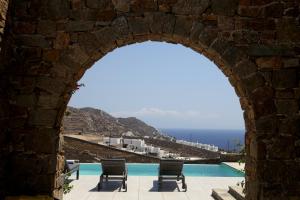 an archway over a swimming pool with a view of the ocean at Niriides Homes & Villas in Elia Beach