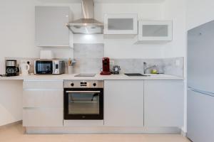uma cozinha com armários brancos e um forno em La Cantonade - Nice T2 with garage for 4 people near Beach em Annecy