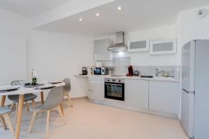 uma cozinha com armários brancos e uma mesa e cadeiras em La Cantonade - Nice T2 with garage for 4 people near Beach em Annecy