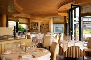un restaurante con mesas y sillas blancas y ventanas en Hyllit Hotel en Amberes