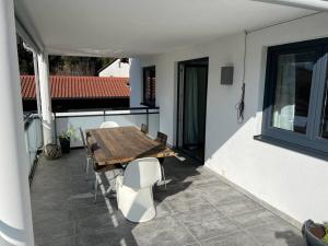 a patio with a wooden table and chairs on a balcony at Gemütliche Wohnung mit großer Terrasse in Bruckmühl