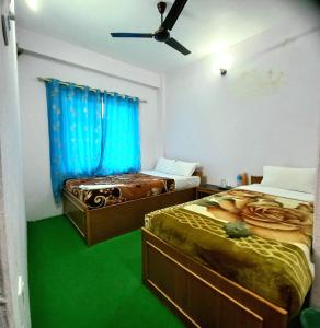 2 camas en una habitación con suelo verde y cortinas azules en Hotel Aarjan And Restaurant, en Pokhara