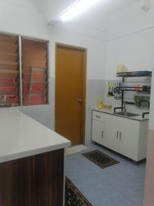 eine Küche mit weißen Arbeitsflächen und einer braunen Tür in der Unterkunft Selesa Inn Homestay in Nilai