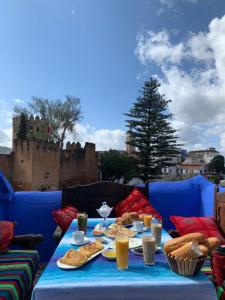 シェフシャウエンにあるHotel Al kassabaの青いソファーの上にテーブルと飲食