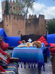 a patio with a blue table and a castle in the background at Hotel Al kassaba in Chefchaouene