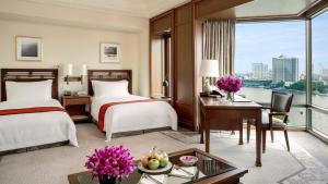 a hotel room with two beds and a desk at The Peninsula Bangkok - SHA Extra Plus in Bangkok