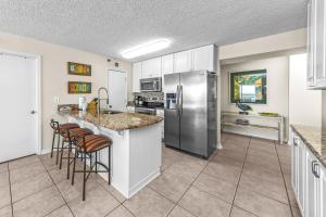 a kitchen with a refrigerator and some bar stools at Harbour Place 313 in Gulf Shores