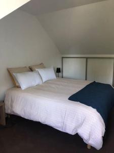 um quarto com uma cama grande com lençóis brancos e almofadas em Cottage 102 em Saumur