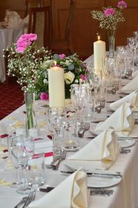 een lange tafel met witte borden, kaarsen en bloemen bij Damson Dene Hotel in Bowness-on-Windermere