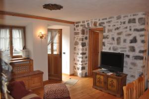 a living room with a tv and a stone wall at La Casa di Nicky - San Vito di Cadore in San Vito di Cadore