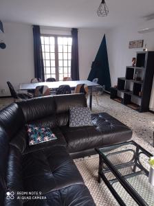 a living room with a black leather couch and a bed at El terret in Sigean
