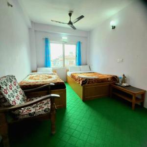 a room with two beds and a chair and a window at Hotel Aarjan And Restaurant in Pokhara