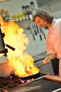 a man cooking food in a pan with flames at Damson Dene Hotel in Crosthwaite