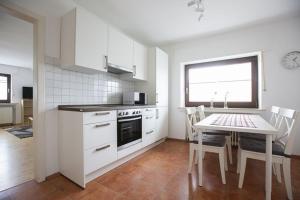 - une cuisine blanche avec une table, une table et des chaises dans l'établissement Ferienwohnung 120, à Schloß Holte-Stukenbrock