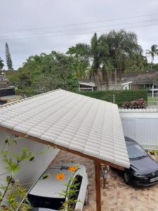 um telhado branco numa casa com um carro por baixo em Suites 500m Praia da Enseada no Guarujá