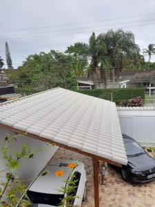 a white roof on a house with a car under it at Suites 500m Praia da Enseada in Guarujá