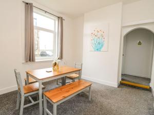 ein Esszimmer mit einem Tisch, Stühlen und einem Fenster in der Unterkunft Annielea is a cosy 3 bed Cottage in Helensburgh in Helensburgh