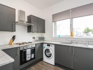 eine Küche mit einer Waschmaschine und einem Waschbecken in der Unterkunft Annielea is a cosy 3 bed Cottage in Helensburgh in Helensburgh