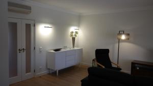 a living room with a white cabinet and a black chair at Vila Atlantida Apartment in Vilamoura