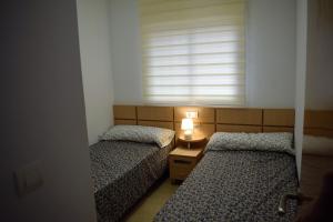 2 Betten in einem kleinen Zimmer mit Fenster in der Unterkunft Valparaiso Marina Dór Planta 7 in Oropesa del Mar