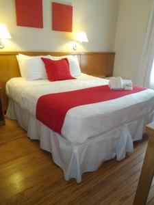 1 dormitorio con 1 cama grande con almohadas rojas y blancas en Hotel Rex, en Piriápolis