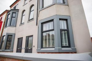 una casa con ventanas negras y persianas blancas en Withnell Stays - Apartment Two en Blackpool