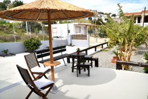 a patio with a table and chairs and an umbrella at PLUMERIA HOUSE in Archangelos