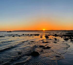 a sunset on the beach with a boat in the water at Kinloch Hotel, Isle of Arran in Blackwaterfoot