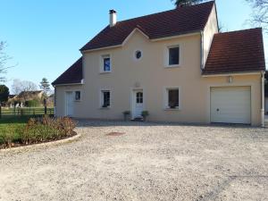 a white house with a garage on a gravel driveway at Le Clos des Roses in Chorey-lès-Beaune