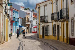a couple of people walking down a street with buildings at Cardume House by Hi Alentejo in Sines