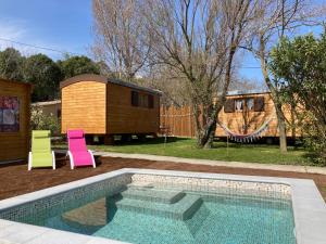 a swimming pool with two chairs and a tiny house at Roulottes & SPA du pont des charrettes in Uzès