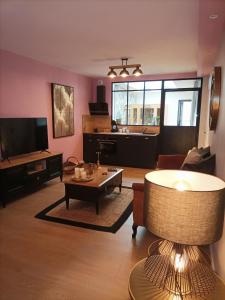 uma sala de estar com um sofá e uma mesa em L'Entracte et son spa privatif em Esquelbecq
