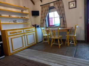 cocina con armarios amarillos, mesa y sillas en Geraghtys Farmyard Pods, en Mayo