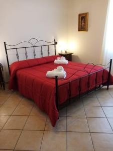 Una cama con sábanas rojas y toallas blancas. en La Giara B&B, en San Demetrio Corone