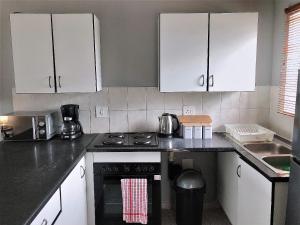 a kitchen with white cabinets and a stove top oven at @Menlyn Place, Menlyn Maine, Pretoria - Accommodation in Pretoria