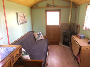 a living room with a couch and a desk at Rosa the Cosy Cabin - Gypsy Wagon - Shepherds Hut, RIVER VIEWS Off-grid eco living in Pedrógão Grande