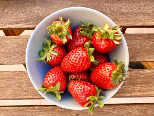 un tazón de fresas sentado en una mesa de madera en Grotto's Paradise B&B, en Għarb