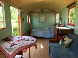 Habitación pequeña con cama y mesa. en Rosa the Cosy Cabin - Gypsy Wagon - Shepherds Hut, RIVER VIEWS Off-grid eco living, en Pedrógão Grande