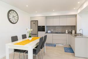 una cucina con tavolo, sedie e orologio di House - sleeps 3 free parking garden & jacuzzi a Estreito da Calheta