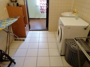 eine weiß geflieste Küche mit einer Spüle und einer Waschmaschine in der Unterkunft Freedom in Uschhorod