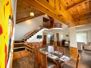 a dining room and living room with a staircase in a house at Nature Bliss - Mount Serene in Manāli