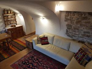 een woonkamer met een witte bank en een stenen muur bij Ronchet Baita Vanoi Trentino in Ronco