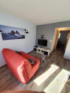 sala de estar con sofá rojo y TV en L'Edelweiss, en Pontamafrey